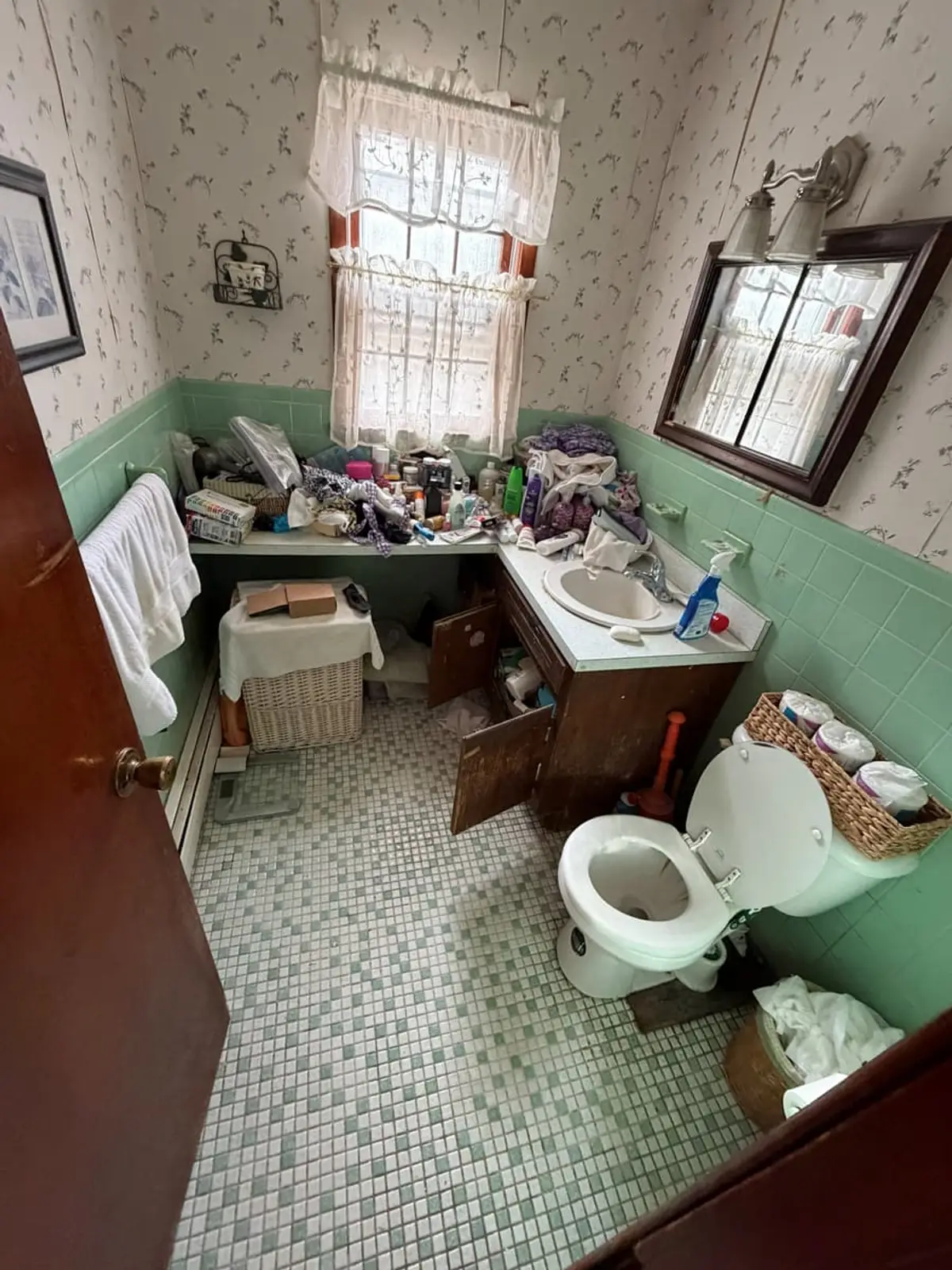 Selling estate property as an executor in Northport: dated bathroom with green tile and a crowded vanity