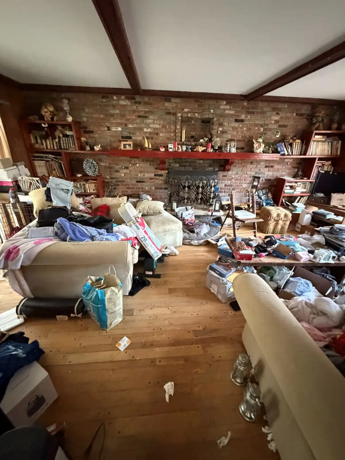 Selling a hoarder house in Northport: den with a brick fireplace wall and belongings everywhere