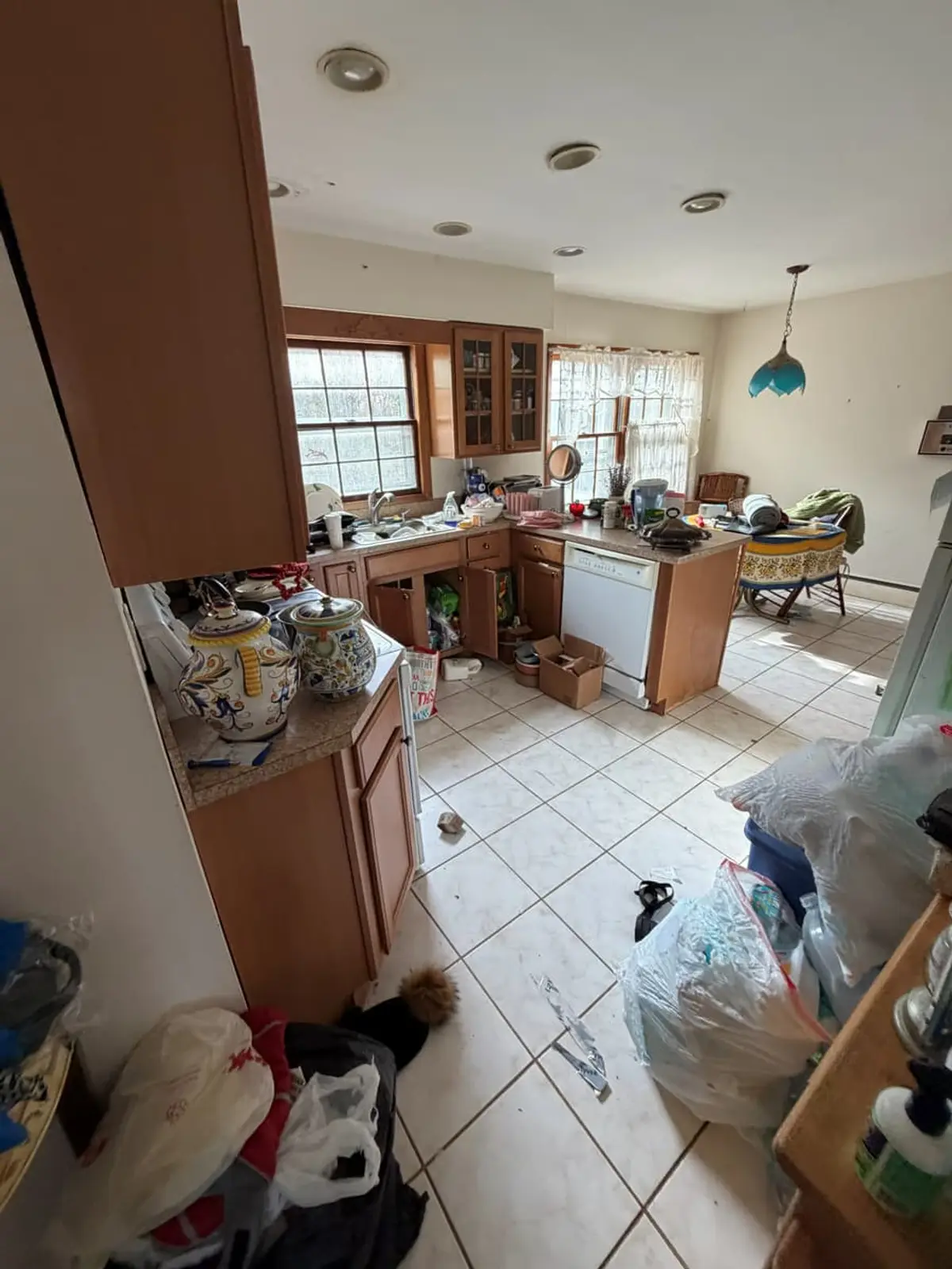 Selling a house after a life change in Northport: kitchen with oak cabinets and bags piled on the tile floor