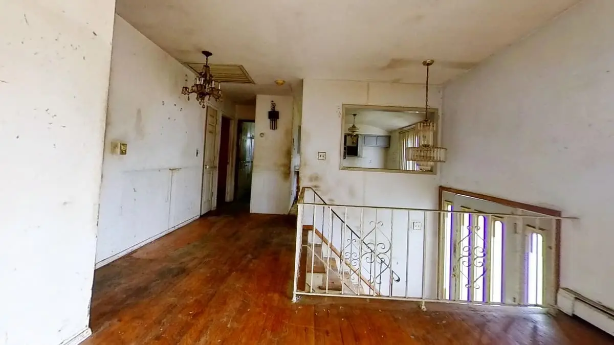 Selling a rental property in Northport: living room with scuffed walls and a worn wood floor