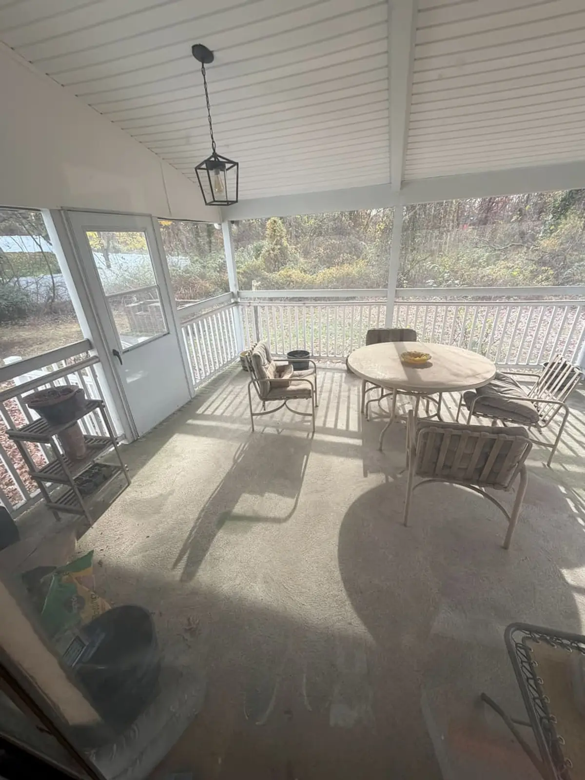 Wondering what your Northport house is worth: screened porch with patio furniture and woods beyond