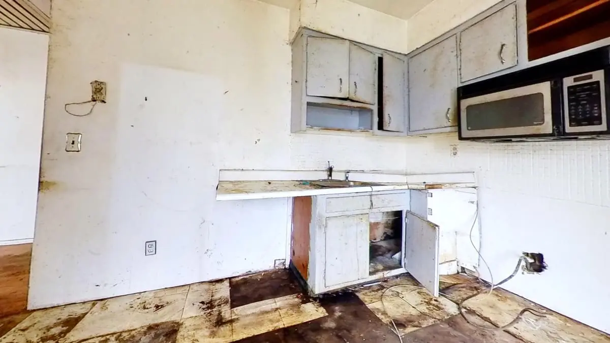 Selling a fire-damaged house in Northport: stripped kitchen with missing cabinets and a damaged floor