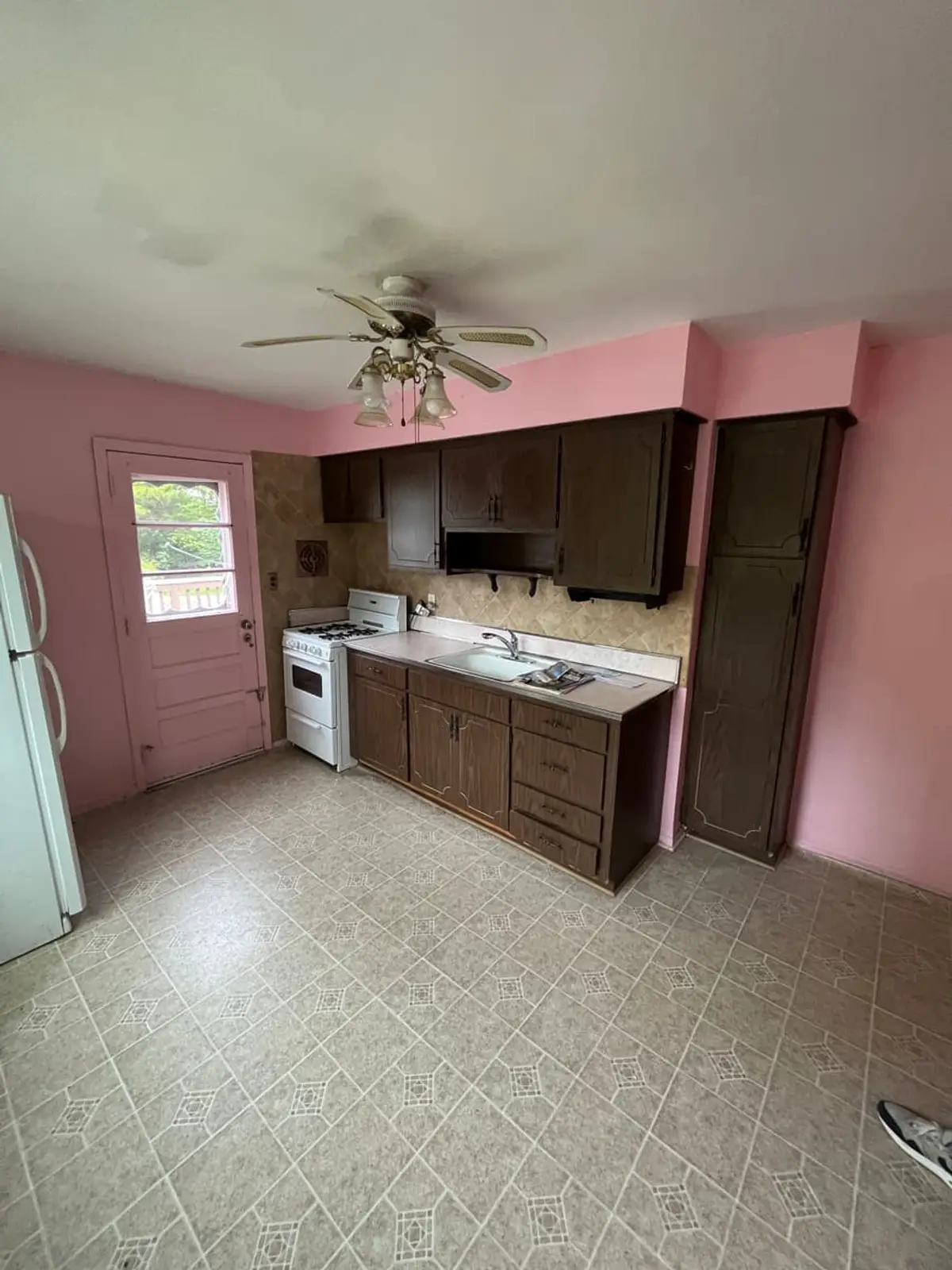 Trying to stop a foreclosure in Northport: vacant pink kitchen with dark cabinets and vinyl floor