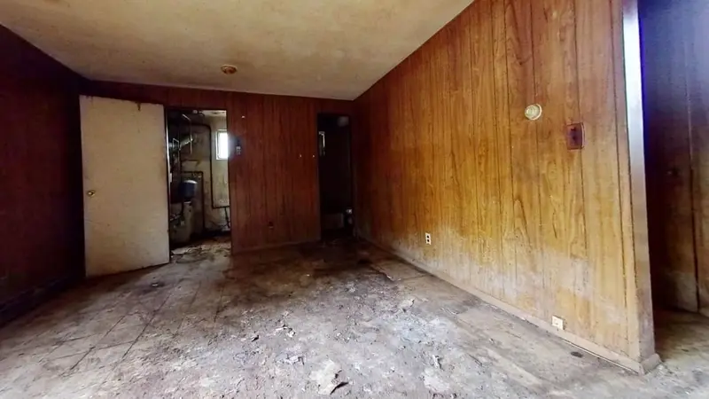 Wood-paneled room with a stained, bare subfloor, Northport, NY