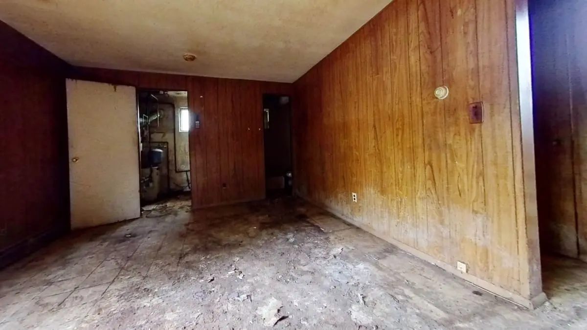 Selling a house with multiple heirs in Northport: wood-paneled room with a stained, bare subfloor